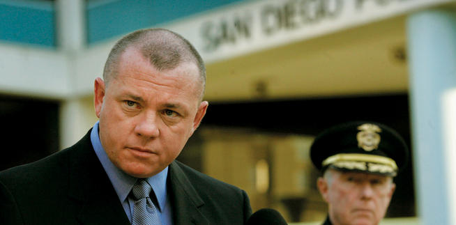 Homicide Detective Lt. Kevin Rooney ’84 speaks at a press conference regarding a murder suspect in front of San Diego police headquarters in 2006. The suspect was arrested a few months later after a nationwide manhunt. In the background is San Diego Police Chief William Lansdowne.PHOTO: COURTESY OF THE SAN DIEGO UNION-TRIBUNE